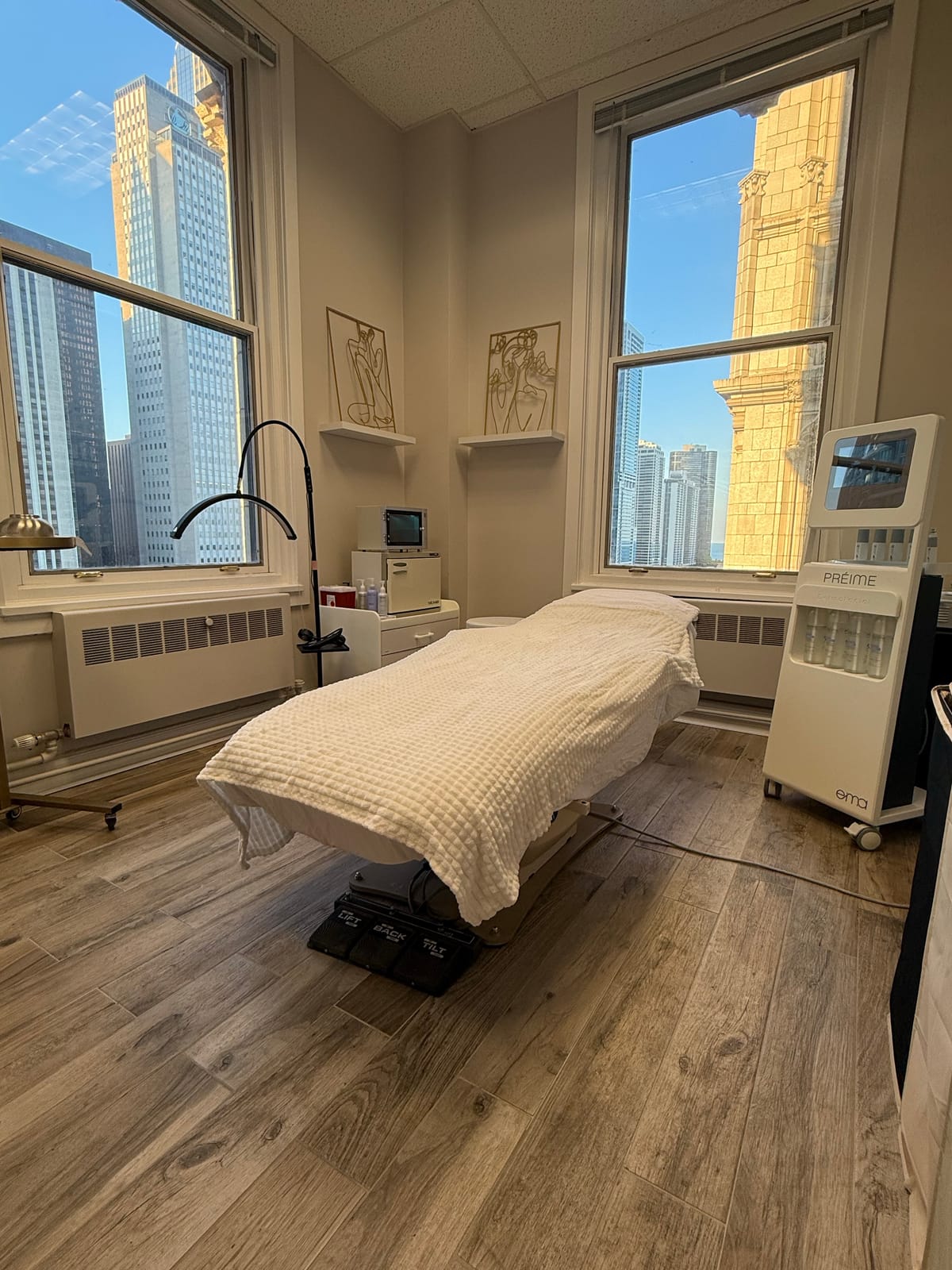 Chicago Medspa exam room with a treatment bed and downtown Chicago views through tall windows